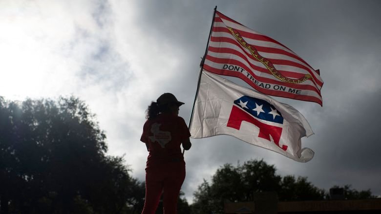 A Republican supporter holds flags outside of a polling place in Uvalde, Texas, on November 8, 2022, during the year's midterm election.